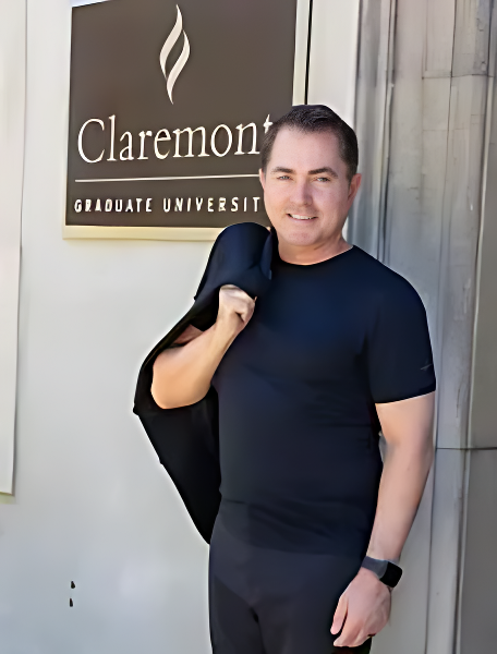 A man in black shirt and jacket standing outside of claremont graduate university.